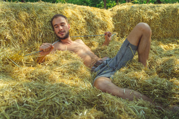 Man or macho in shorts lying in hay, the hay after harvest, hay agricultural with collected crops.