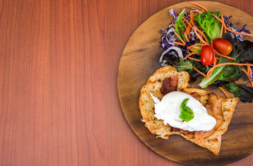 Homemade meal, Organic egg benedict with fresh salad on wood plate for healthy breakfast in wood background