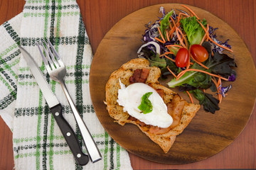 Homemade meal, Organic egg benedict with fresh salad on wood plate for healthy breakfast in wood background
