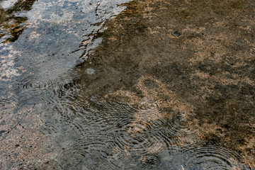 Raindrop falling on the cement floor and waving water in rainy season.