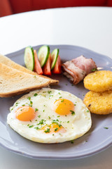 Close up of british breakfast with fried egg, wheat crunchy toasts, potato hash browns, bacon and salad