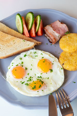 Close up of british breakfast with fried egg, wheat crunchy toasts, potato hash browns, bacon and salad