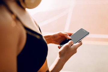 Close - up of sporty girl using smartphone after workout, outdoors