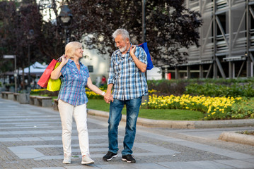 Happy senior couple with shopping bags looking at each other