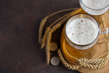 two glass mugs of wheat beer and ears of wheat with copyspace