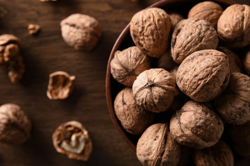  Walnuts nuts in a bowl on a dark brown wooden background in a dark key