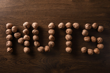  Inscription of walnut nuts on a dark brown wooden background in a dark key