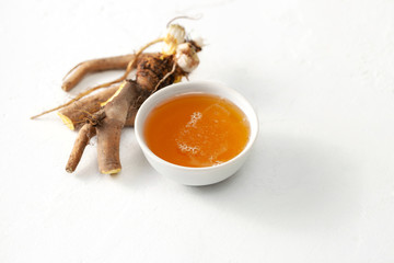 Raw root plant Rumex crispus (yellow dock) and honey on white concrete background