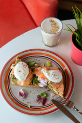 Fancy breakfast with soft waffle, mashed avocado, salmon, poached egg and coffee