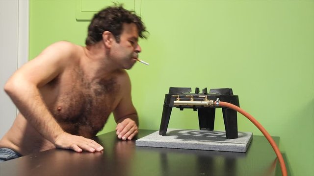 Man with the naked chest goes to kitchen and lights a cigarette