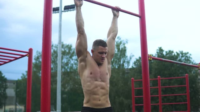 Muscular man doing abs exercise during his workout on the street 