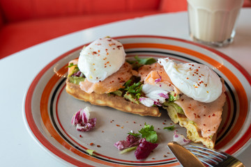 Close up of healthy ketogenic breakfast: soft waffle, mashed avocado, salmon, poached egg and coffee