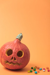 Halloween pumpkin with candies on orange background