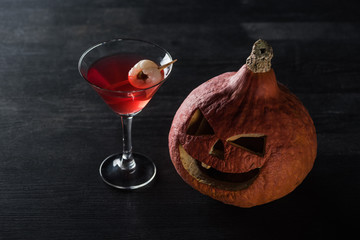 Halloween pumpkin and red cocktail on black background