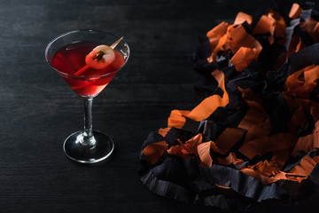 red tasty cocktail near Halloween decoration on black background