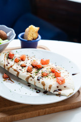 Traditional mexican quesadilla with fried chicken and tomatoes stuffed in a wheat tortilla and sprinkled with spicy sauce