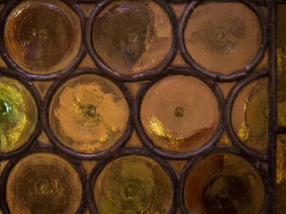 Wall of glass bottles with light in background.
