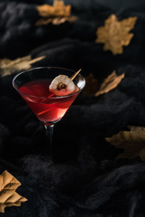 red cocktail with maple dry yellow leaves on black background
