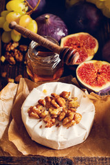 Camembert cheese with figs, walnuts, honey and thyme served for a dinner in dark key on  wooden...