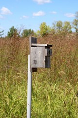 A close view of old wooden birdhouse in the grass field.