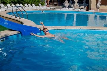 child dives from the side into the blue pool in the hotel courtyard