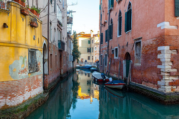Fototapeta na wymiar Boats on narrow canal between colorful historic houses in Venice.