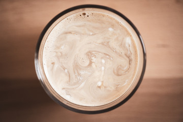 Top view of glass with coffee on a wooden board background