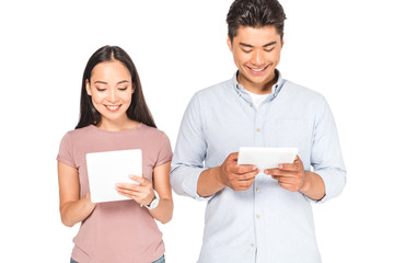 cheerful asian couple using digital tablets isolated on white