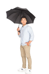 handsome asian man standing under umbrella, holding hand in pocket and looking away on white background
