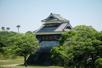 Landscape of historic fortress construction at Kumamoto Castle, overlooking trees and river.