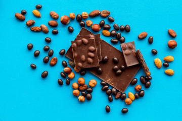 Chocolate with nuts and its ingredients on blue background top view