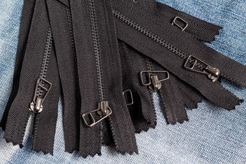 Pack a lot of black metal antique zippers stripes with sliders pattern for handmade sewing tailoring haberdashery leather craft on the blue denim background