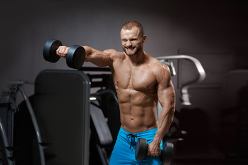 Fototapeta na wymiar Handsome bodybuilders grimace of effort posing with dumbbells in modern gym