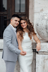 Fototapeta na wymiar Stunning young couple. Family photo, romantic couple. Best time. Young man in grey suit embrase young wonderful woman in white dress