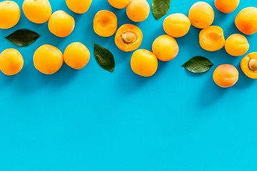 Fruit frame. Apricots and leaves on blue background top view copy space