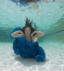 A dark haired women model in various outfits underwater.