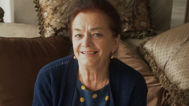 Portrait of happy elderly woman looking at camera and smiling with teeth.