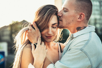 Tanned young caucasian couple, modern lovestory in film grain effect and vintage style. Sunset, summer evening. Honeymoon concept. Toned in teal orange. Close up of tender moments and feeling.