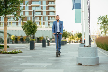 Young businessman in a suit riding an electric scooter © JustLife