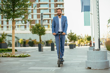 Young businessman in a suit riding an electric scooter © JustLife