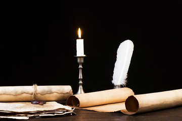 Scrolls of parchment and old papers on the background of a lit candle and inkwell pen