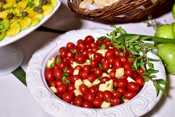 Delicious caprese salad with ripe cherry tomatoes and mini mozzarella cheese balls with fresh basil leaves. Italian healthy food concept with copy space. View from above.