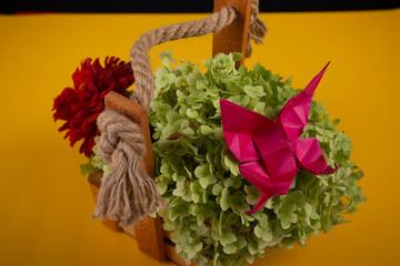 origami butterfly crafted art on a green bush in a basket on a colored background beautiful bouquet studio close shot