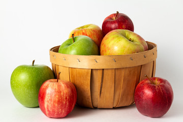 fresh red and green apples in a basket on a white background