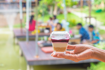 Hand holding cake Background blur people and tree in garden on pond.