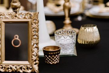 A rectangular frame with a table number stands on a stylish wedding table for guests.