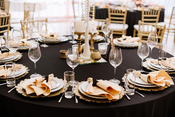 A black tablecloth, expensive utensils and gold details decorate the wedding table