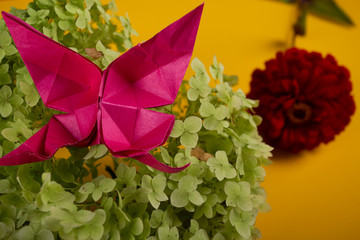 origami butterfly on a green bush in a basket on a colored background beautiful bouquet studio close shot handmade crafted art