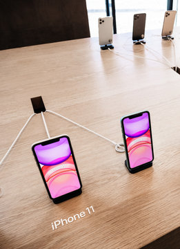 Paris, France - Sep 20, 2019: View from above of new iPhone 11 displayed in Apple Store as they goes on sale - white present shopping bag on wooden table corner - vertical image