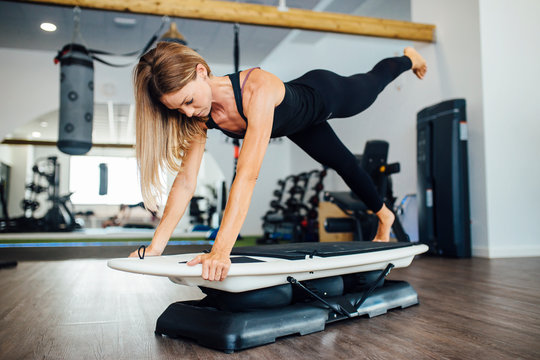 woman training doing plank exercises on a surfboard in the gym